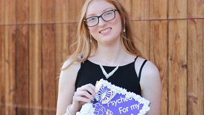 Madalynn Eidson in her graduation attire holding her graduation cap.