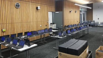Rows of laptops on tables in computer lab.