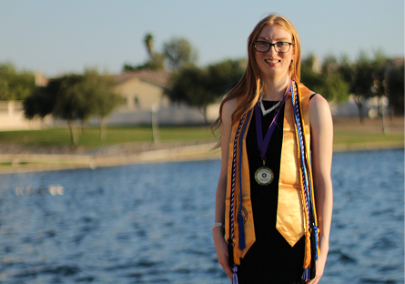 Madalynn Eidson outside in graduation attire near lake.