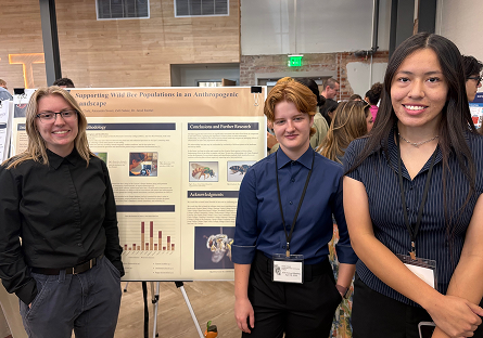 Alex, Arella, and Zalli standing near project poster board.