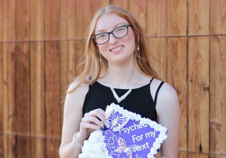 Madalynn Eidson in her graduation attire holding her graduation cap.