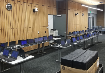 Rows of laptops on tables in computer lab.