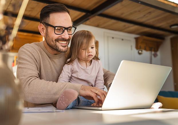 A toddler sitting on her father's lap and looking at computer.