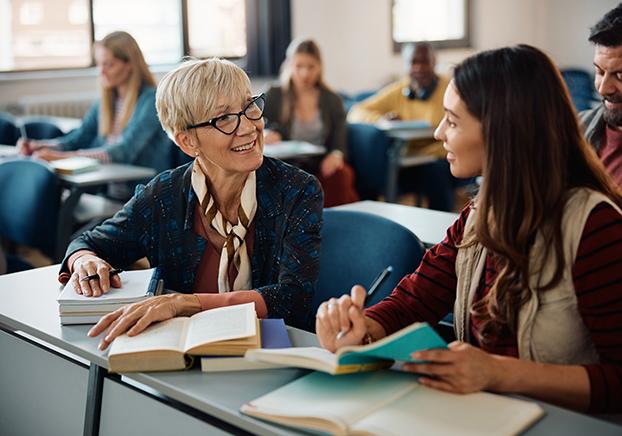A faculty member and a student in classroom chatting.