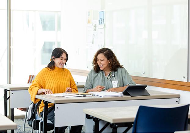 Two students in a classroom chatting.