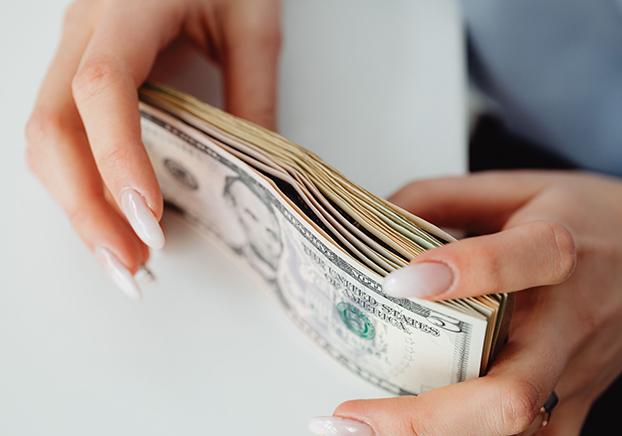 Hands holding dollar bills.